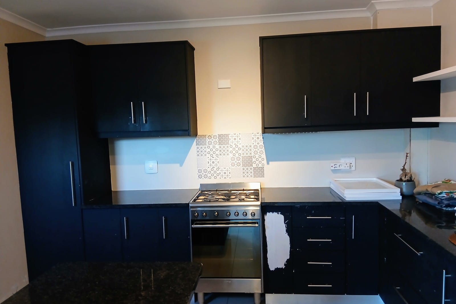 Macassar kitchen cupboards in the original dark blue, with a patch of test paint on one door