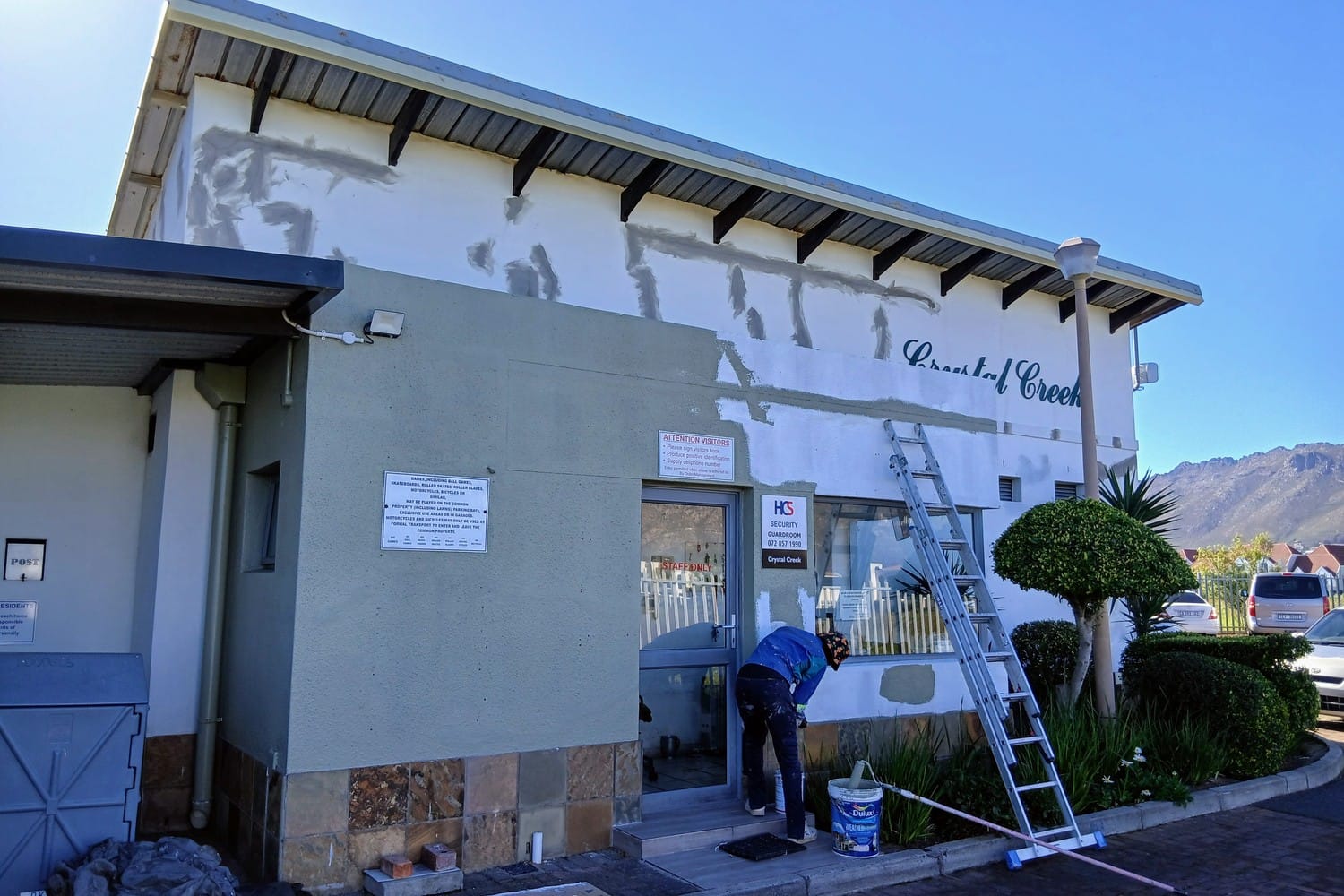 Commercial guardhouse in Gordon's Bay with filler patches across the wall and a painter at work