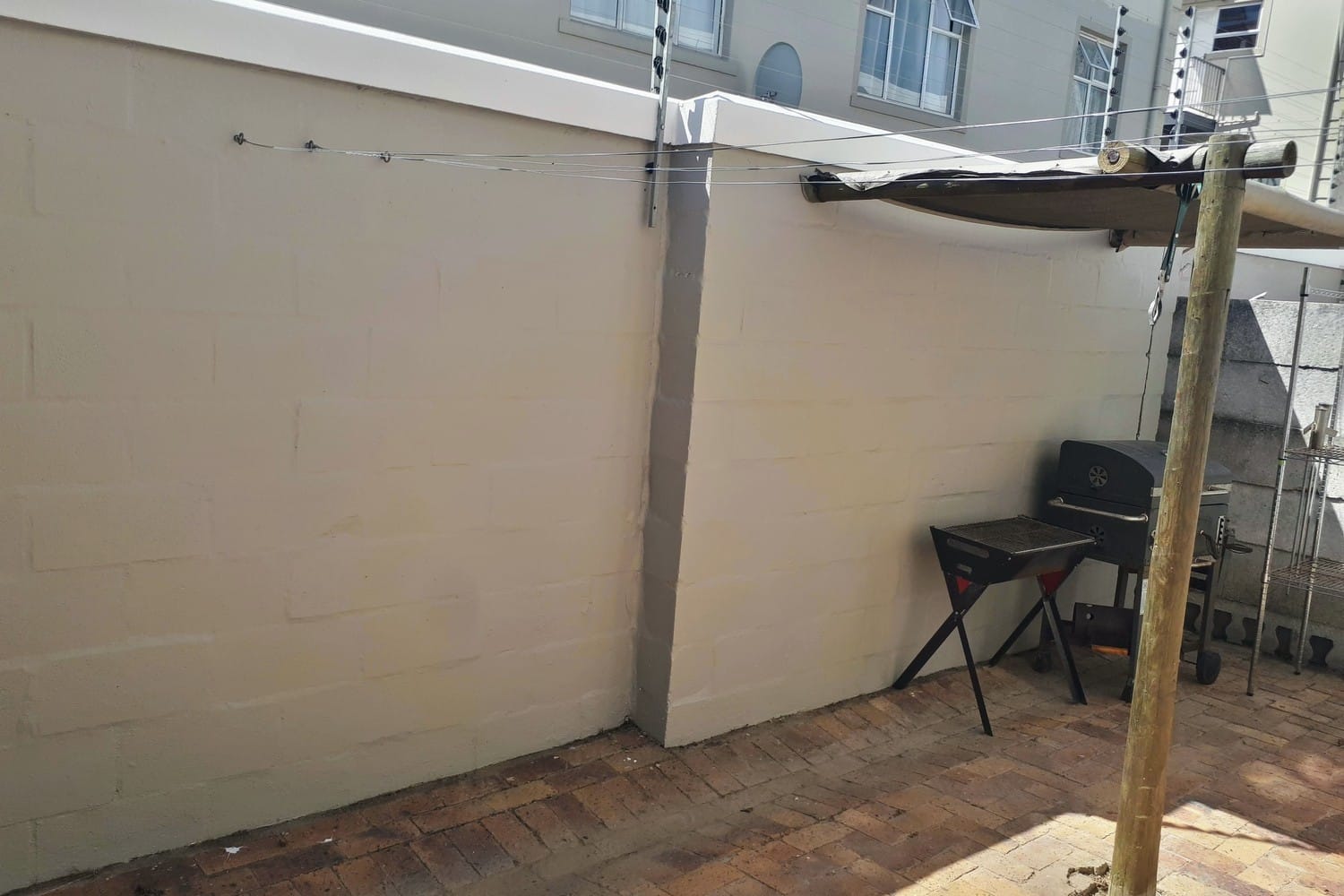 The same Strand wall painted in two coats of one colour above cleared paving