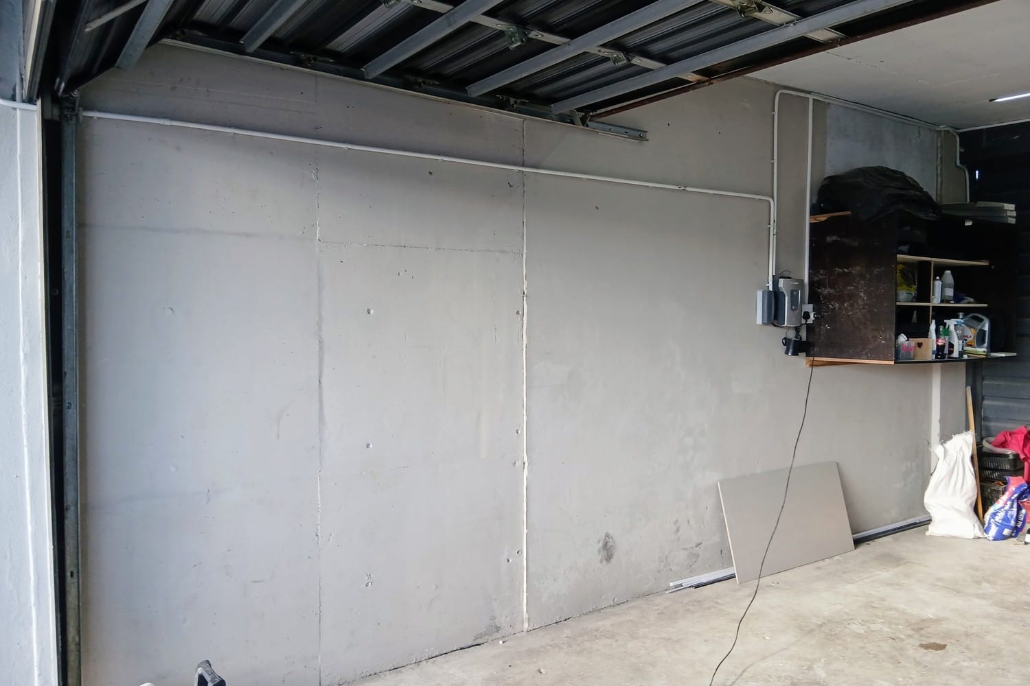 Garage side wall in Strand in bare plaster with stains and clutter in the corner