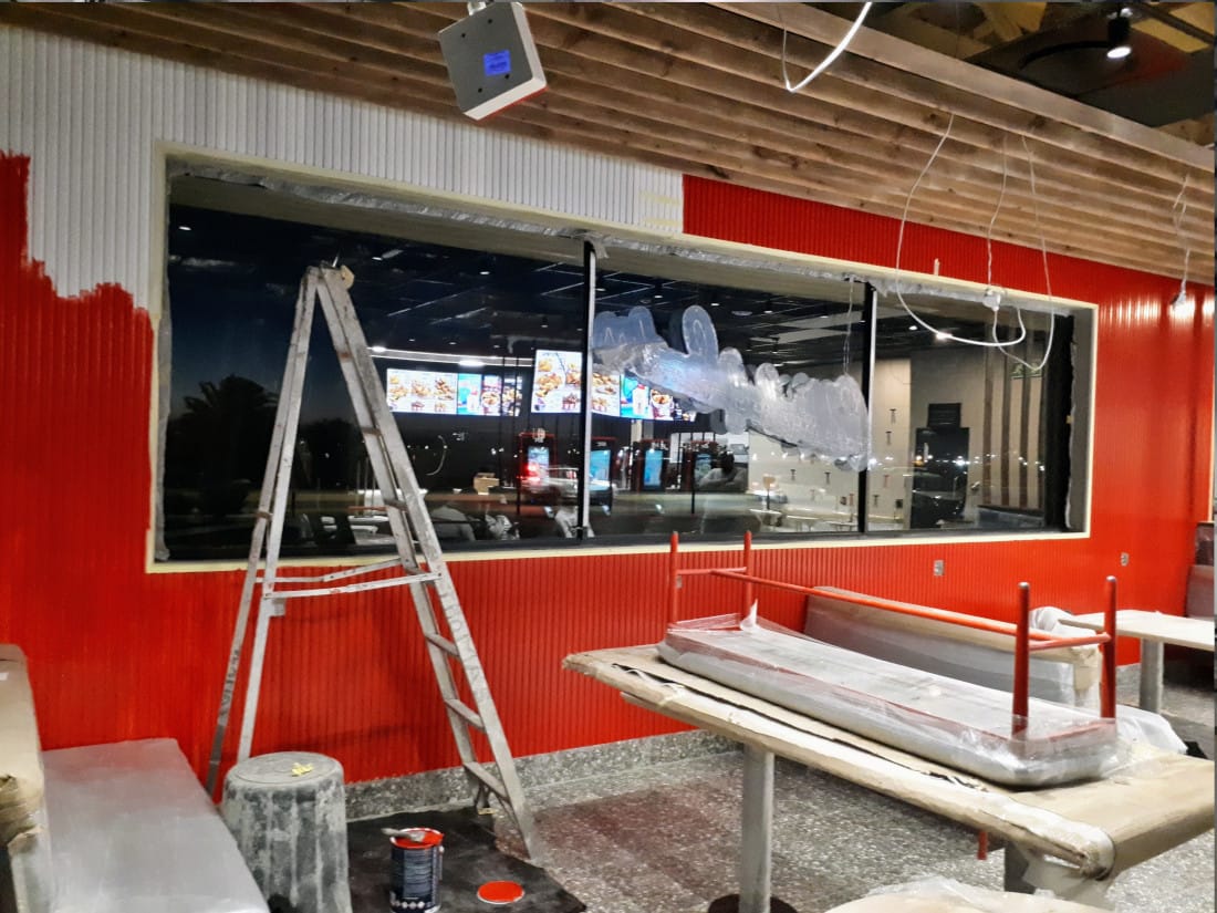 Interior of a commercial restaurant space mid-renovation, red panelling partly painted